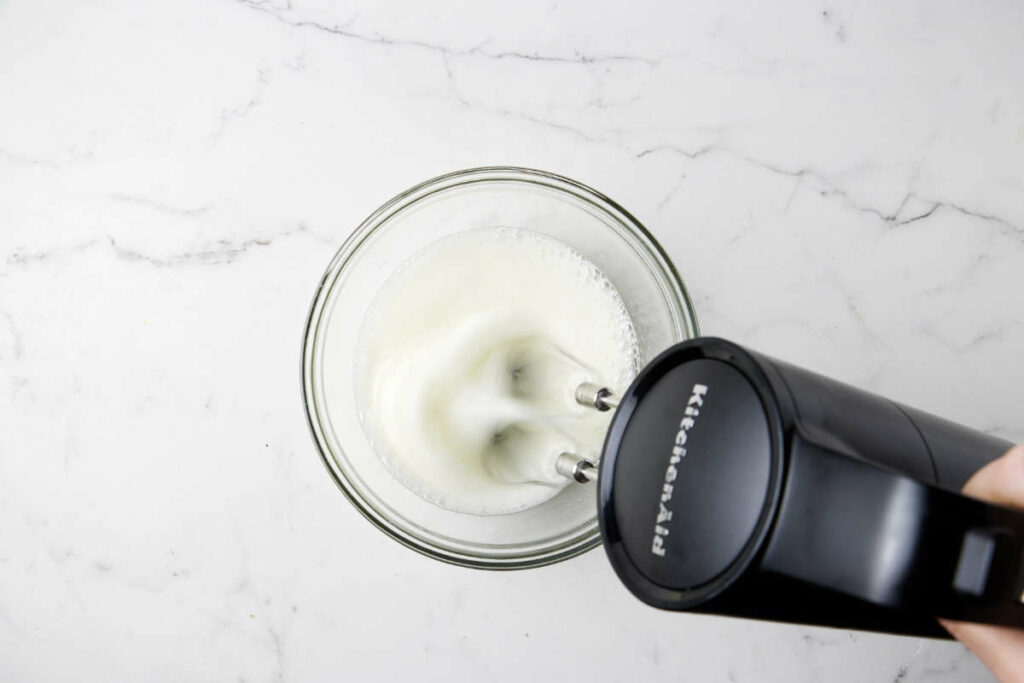 Whipping egg whites in a bowl with an electric mixer.