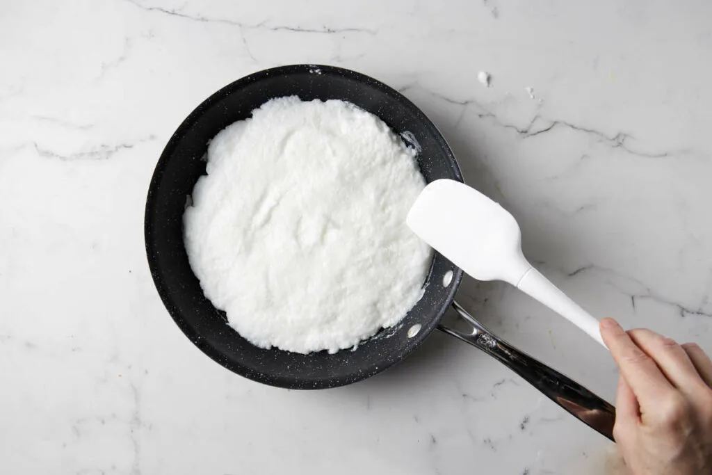 Spreading the egg whites in a skillet.