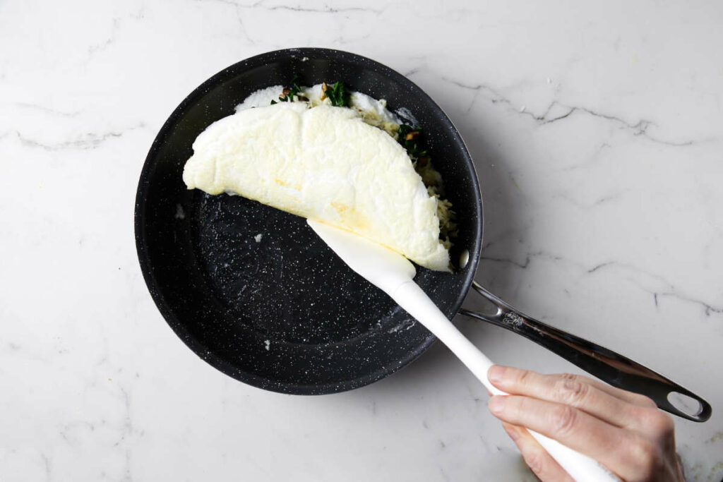 Folding the omelet over the top of the fillings.