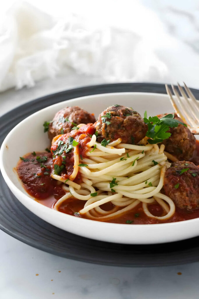 Tomato basil garlic sauce in a bowl with pasta and meatballs.