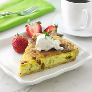 A leek bacon and goat cheese quiche next to a cup of coffee.