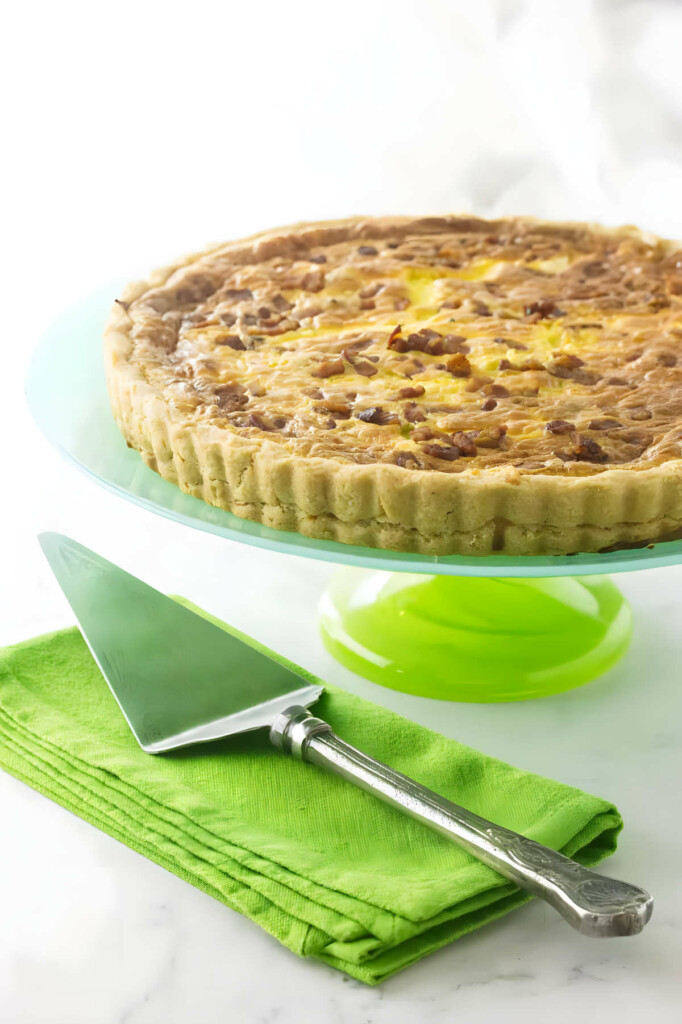 A recipe for goat cheese quiche on a platter next to a spatula.