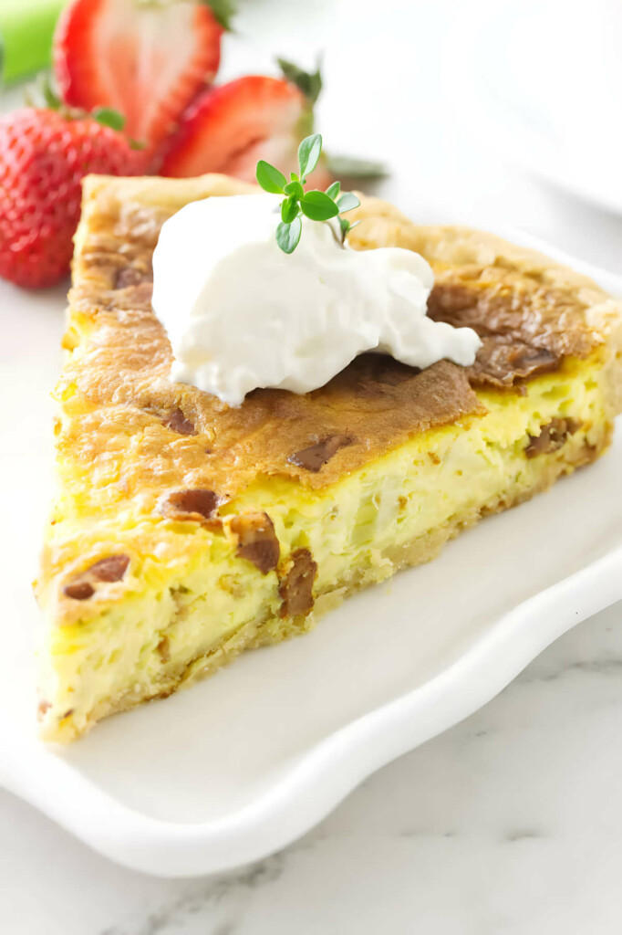 A slice of chevre quiche with a dollop of sour cream on top.