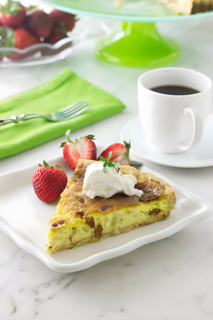 A slice of goats cheese quiche next to a cup of coffee and some strawberries.