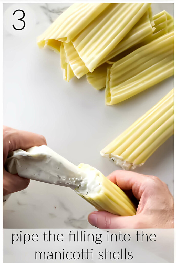 Piping ricotta cheese into a manicotti pasta shell.