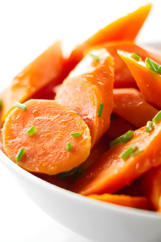 A bowl of steamed carrots topped with herbs.