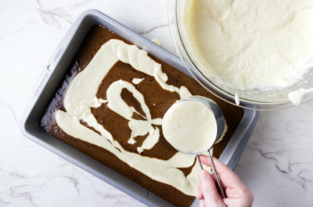 Pouring the ricotta mixture on top of the chocolate cake batter.