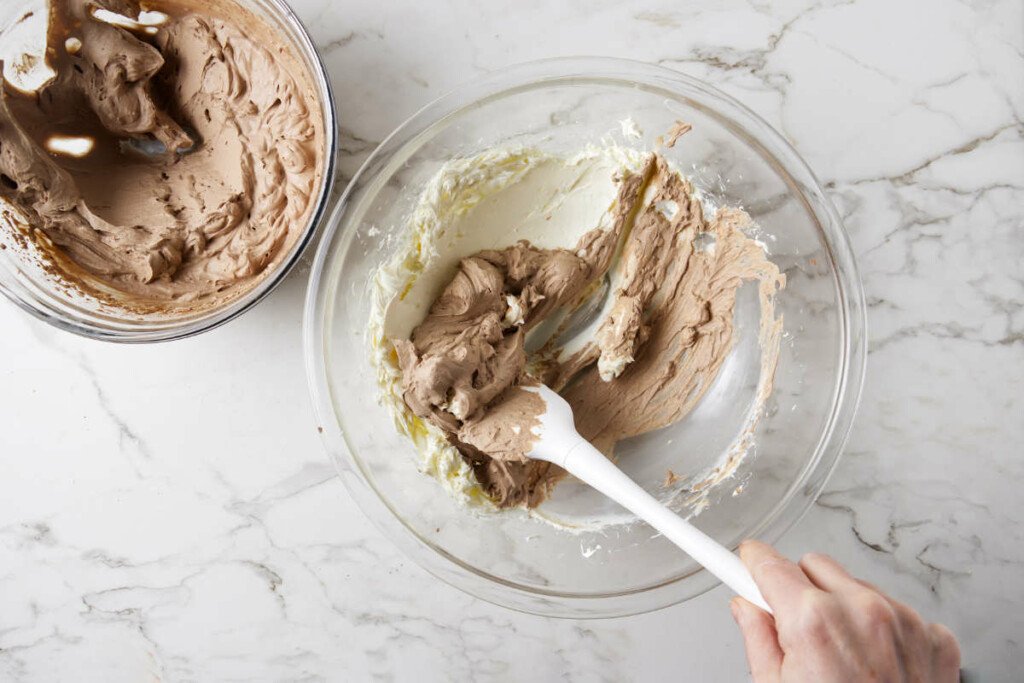 Folding whipped cream into cream cheese to lighten the mixture.