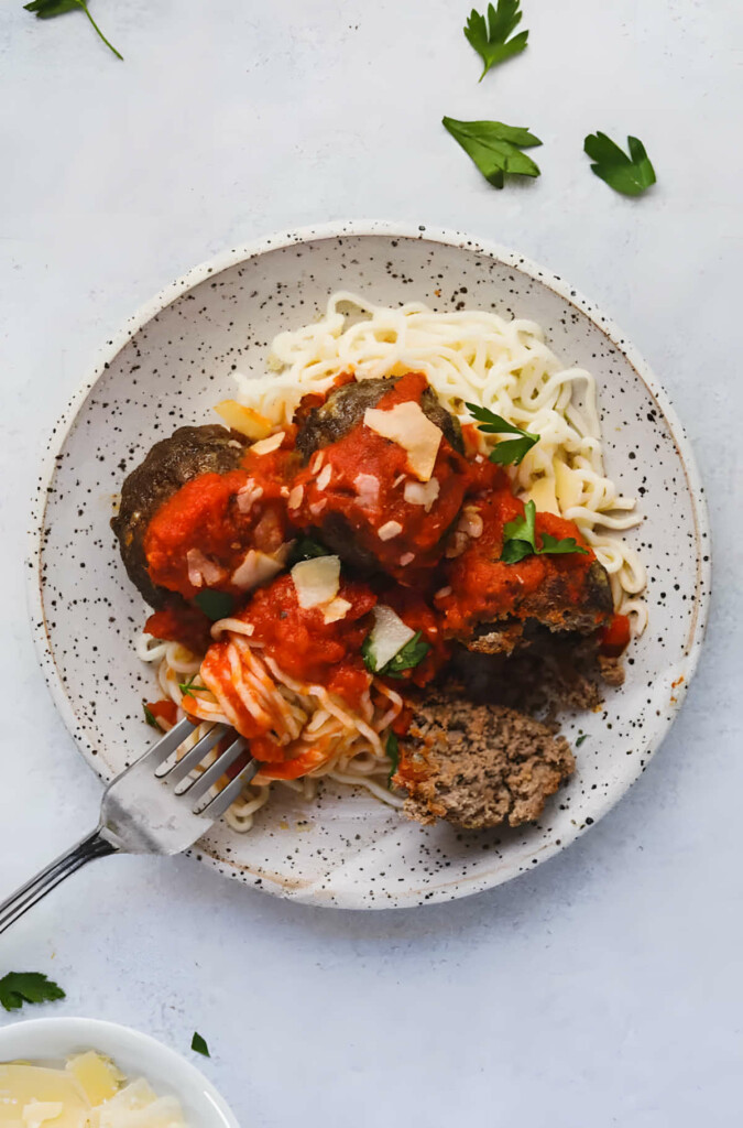 Keto meatballs in a bowl with marinara sauce and noodles.