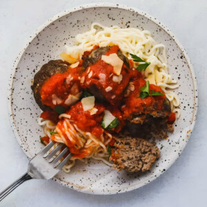 A fork in a bowl with meatballs and spaghetti.