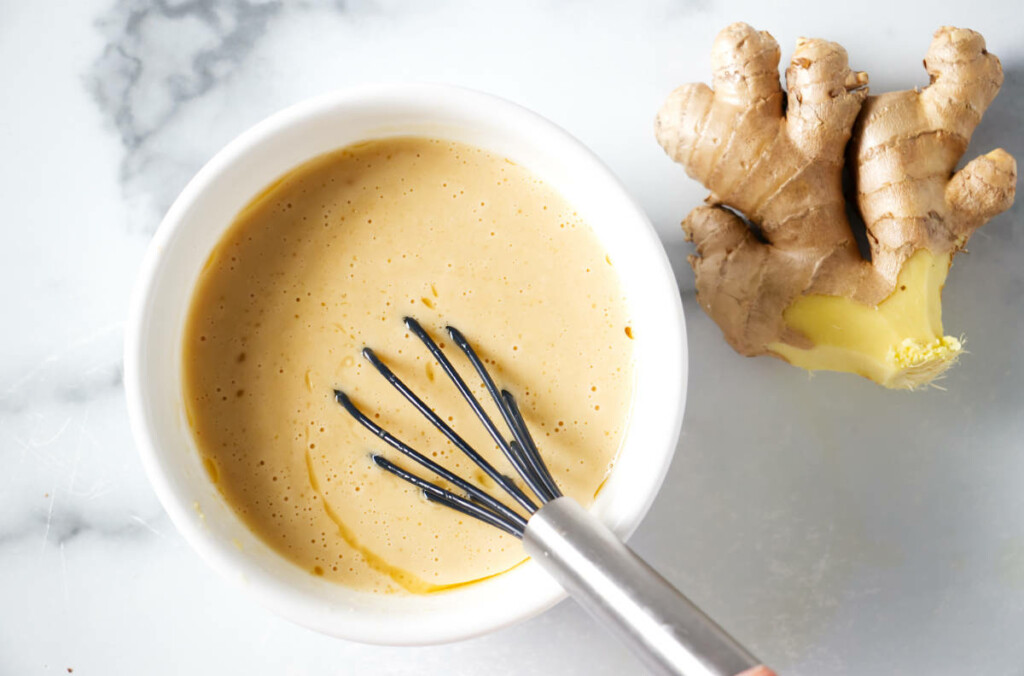 Whisking the dressing together. Ginger root to the right of bowl.