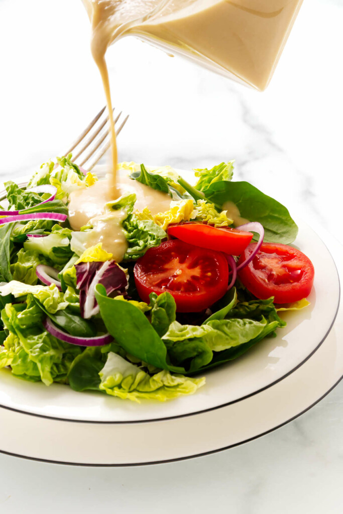 Pouring dressing on a green salad.