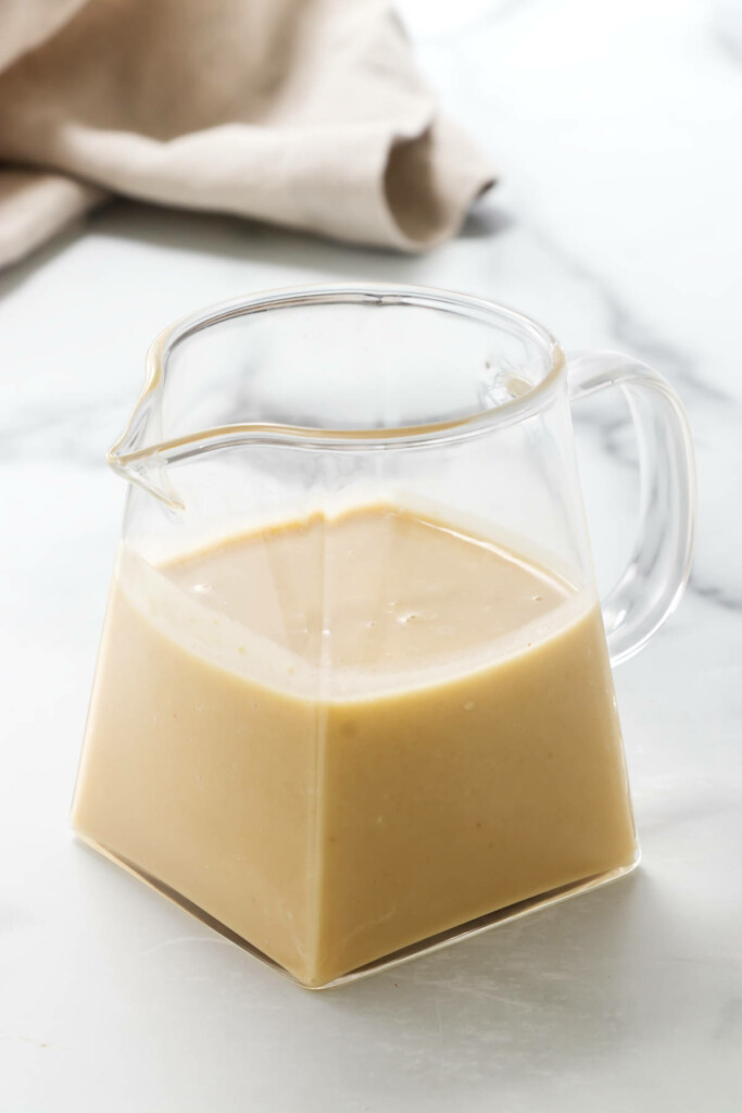 A small pitcher of Miso-Ginger Dressing. A napkin in the background