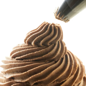 A star tip piping buttercream frosting on a cake.