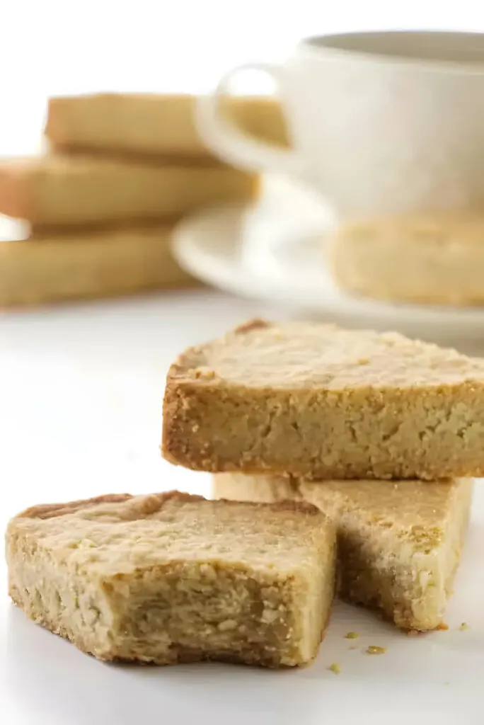 Three oat flour shortbread bars in front of a cup of coffee.