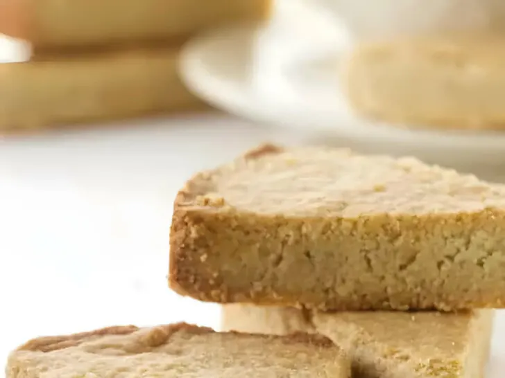 Three oat flour shortbread bars in front of a cup of coffee.