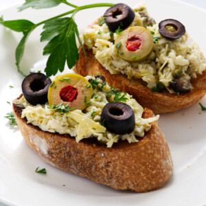 Two toasted baguette slices topped with an artichoke spread.