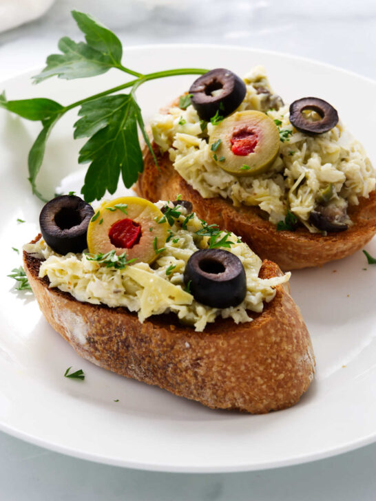 Two toasted baguette slices topped with an artichoke spread.