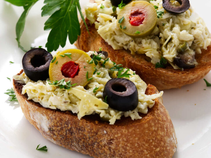 Two toasted baguette slices topped with an artichoke spread.