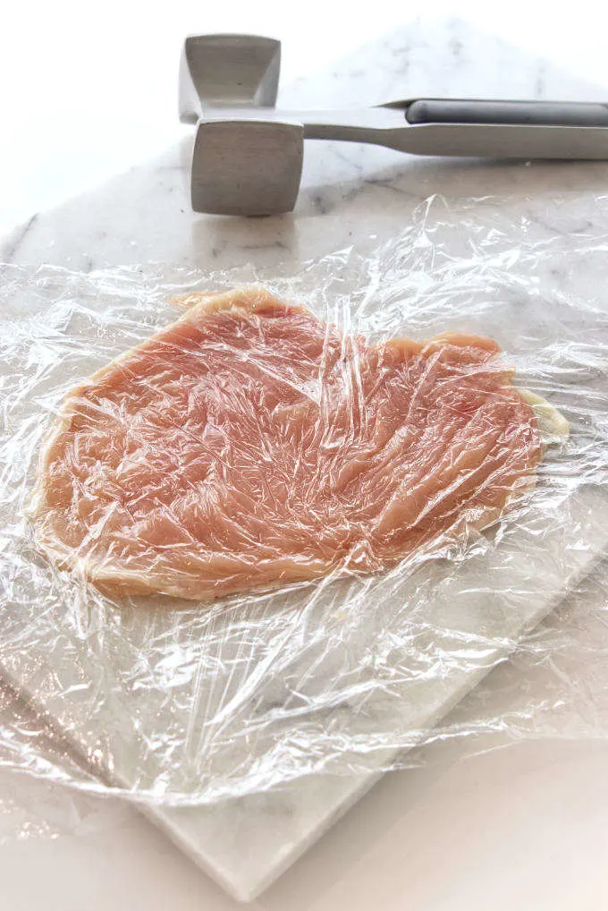 Pounding a chicken breast with a meat mallet.