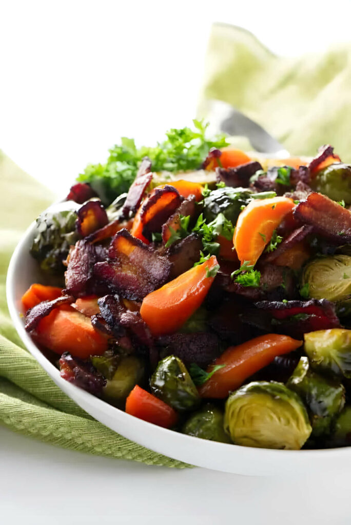 Brussels sprouts and carrot slices in a serving bowl with bacon.