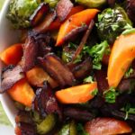 Carrots and brussels sprouts in a serving bowl with bacon.