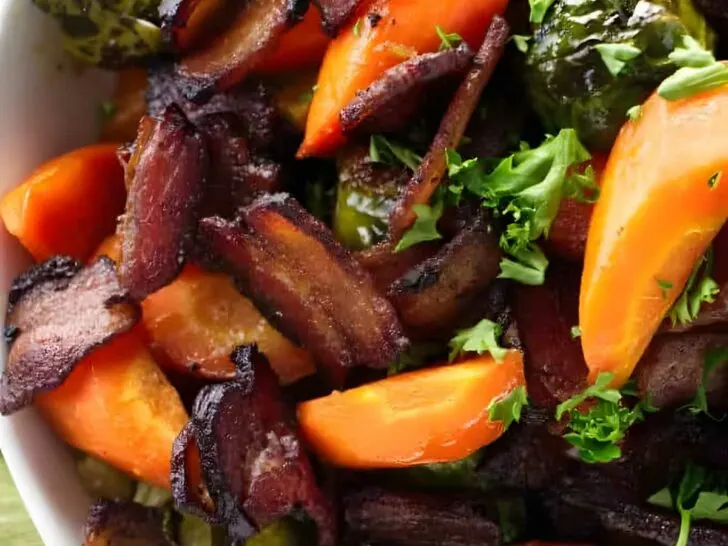 Carrots and brussels sprouts in a serving bowl with bacon.