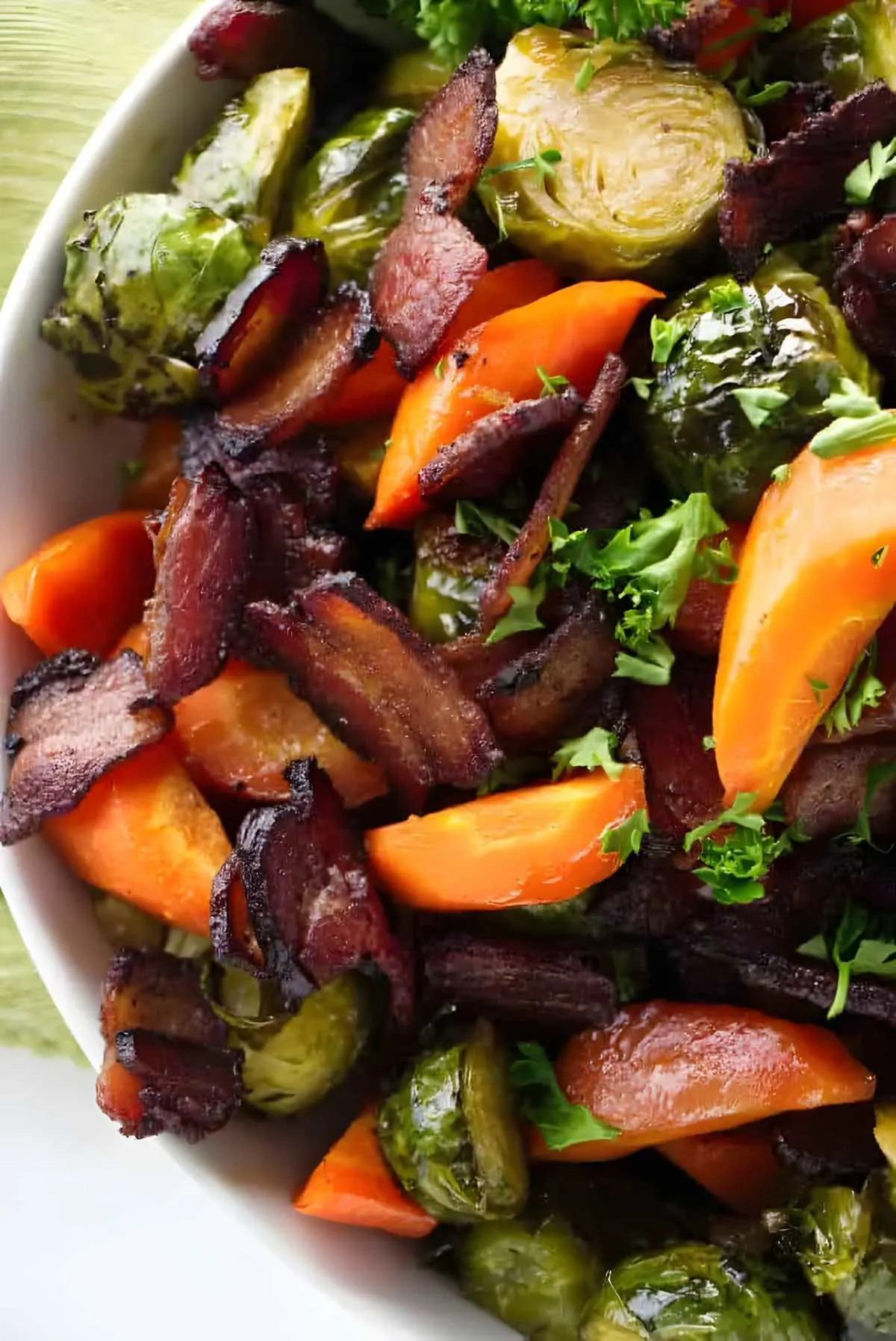 Carrots and brussels sprouts in a serving bowl with bacon.