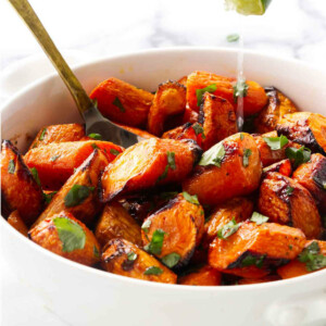 Drizzling lime juice on cilantro carrots in a bowl.