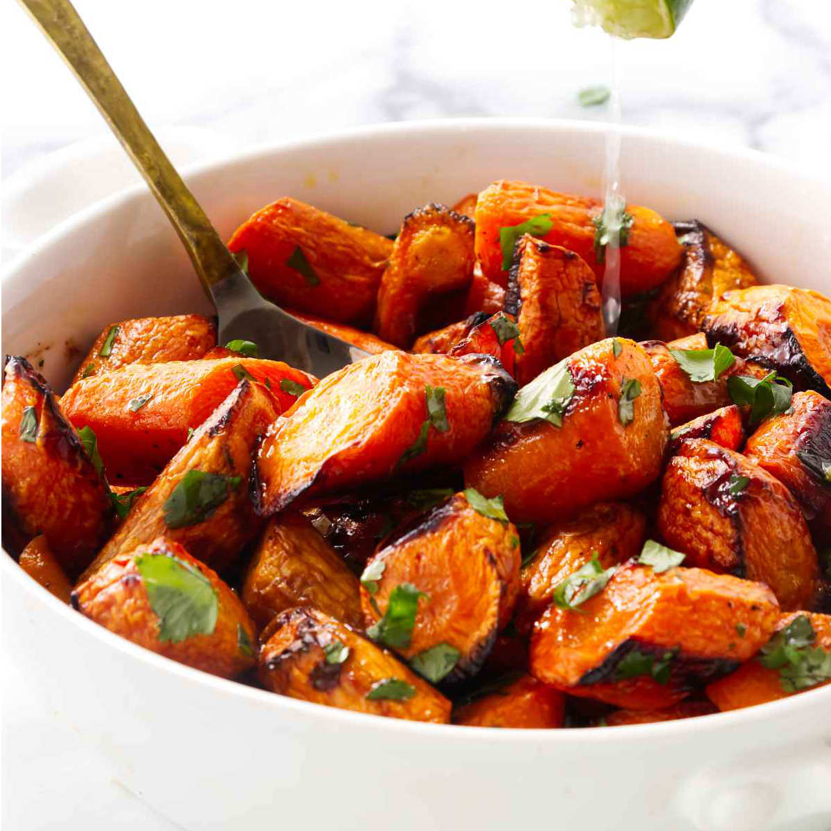 Drizzling lime juice on cilantro carrots in a bowl.