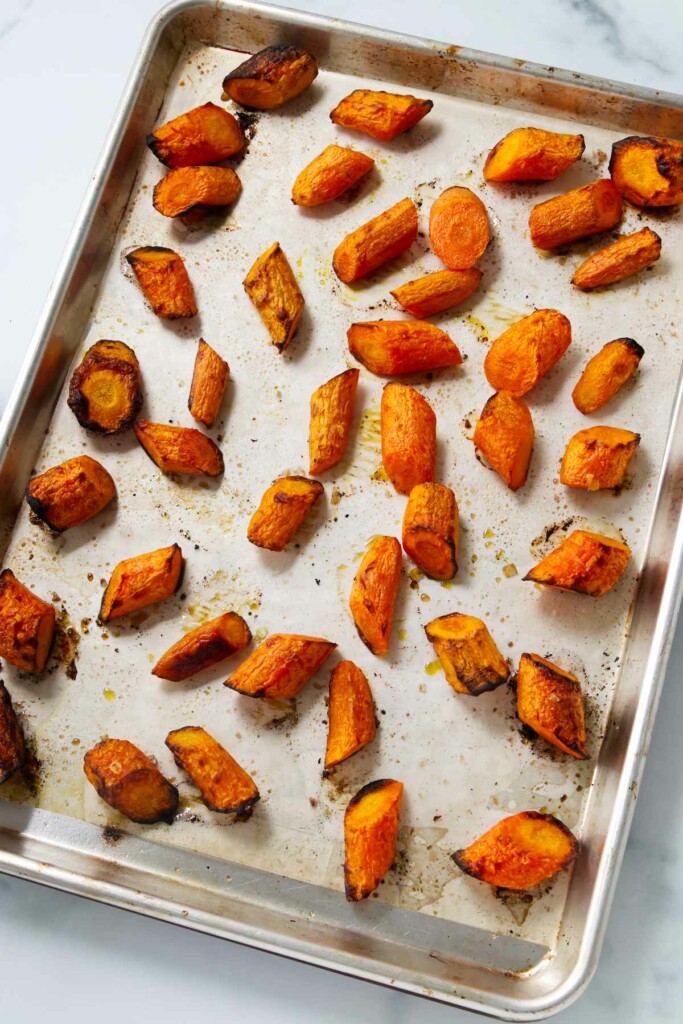 Slices of carrots roasted on a baking pan.