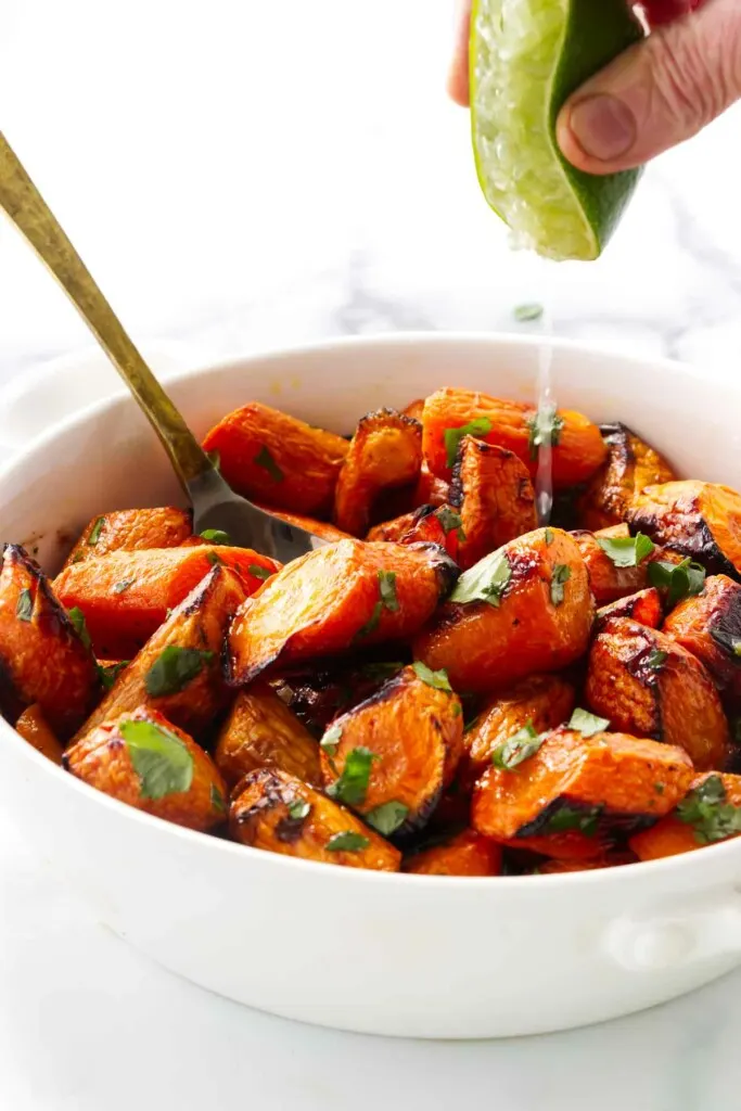 Squeezing lime in a bowl with carrots and cilantro.