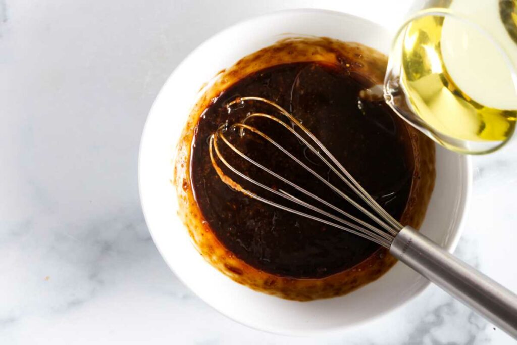 Pouring oil into a bowl with balsamic vinaigrette.