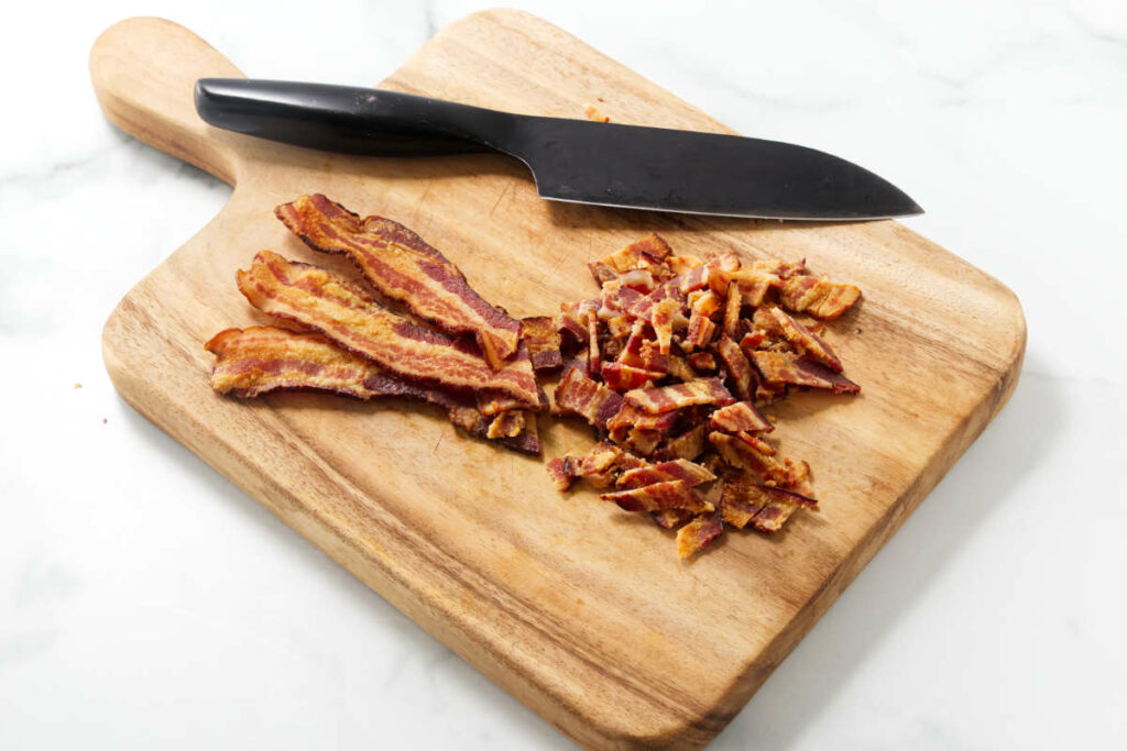 Chopping bacon on a cutting board.