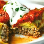 Stuffed cabbage rolls on a plate and topped with sour cream.