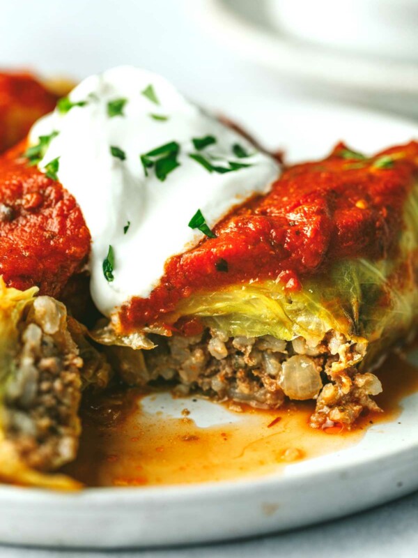 Stuffed cabbage rolls on a plate and topped with sour cream.