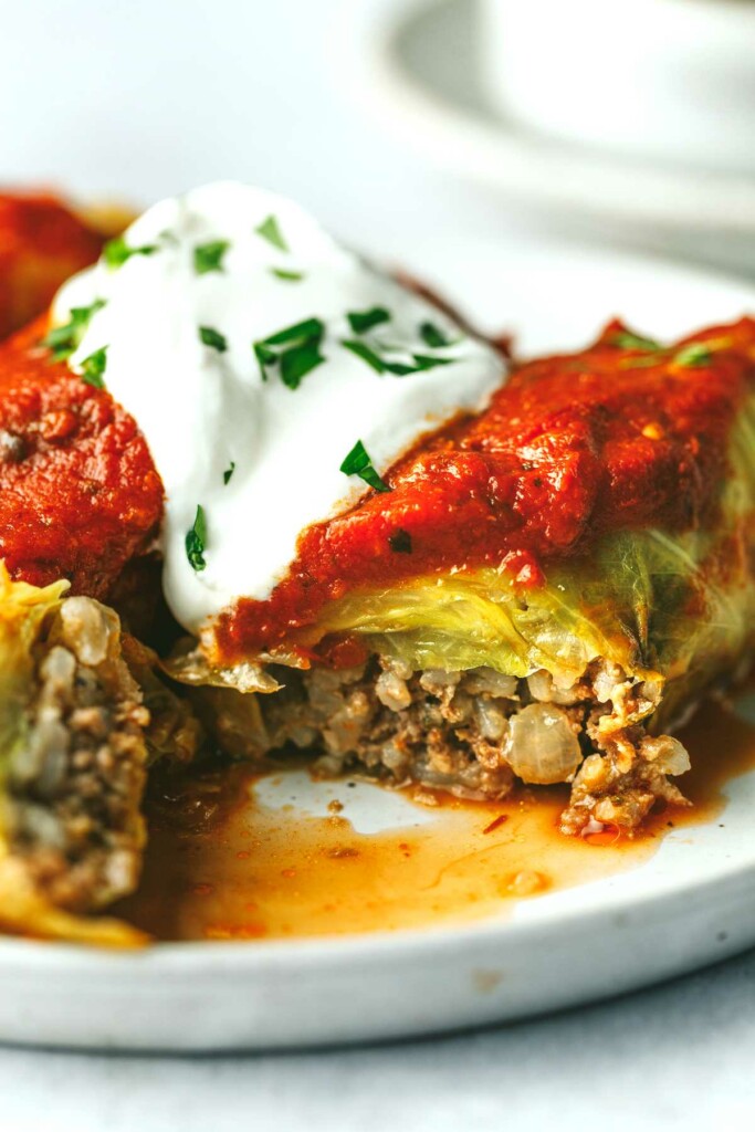 Stuffed cabbage rolls on a plate and topped with sour cream.