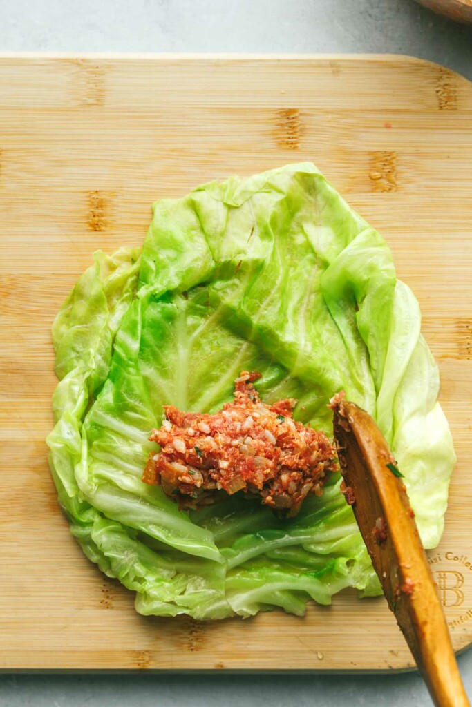 Adding filling for cabbage rolls to a cooked cabbage leaf.