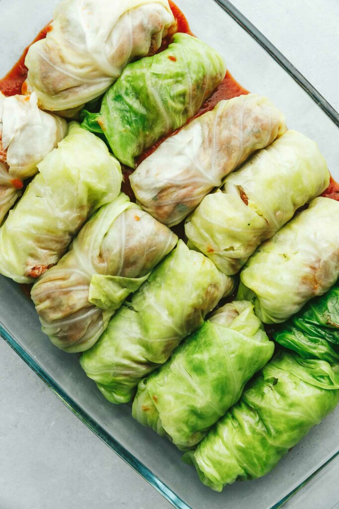 Beef and cabbage rolls in a dish and ready to bake.