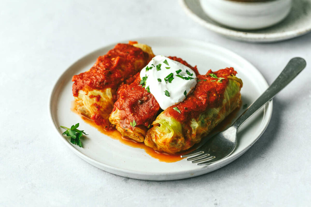 Beef and cabbage rolls on a white dinner plate next to a fork.