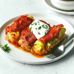 Sausage and beef stuffed cabbage rolls on a plate with a fork.