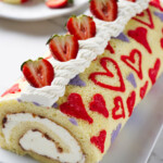 A valentine cake strawberry cake roll on a serving platter.