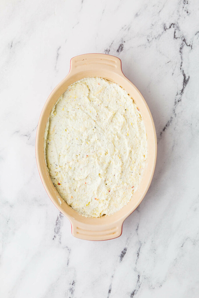 Spreading a ricotta dip recipe into a baking dish.