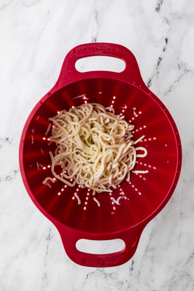 Fresh udon noodles in a colander.