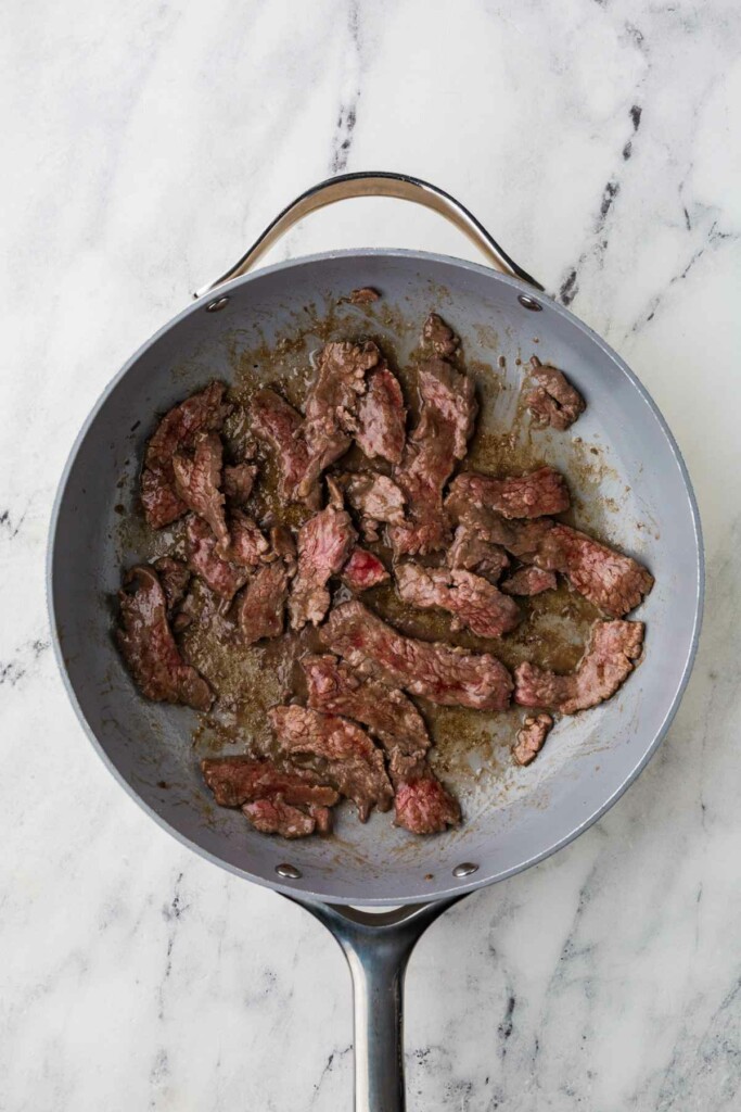 Sliced steak in a skillet to make a beef udon recipe.