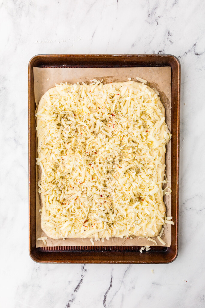 Adding seasoning to show how to make breadsticks with pizza dough.