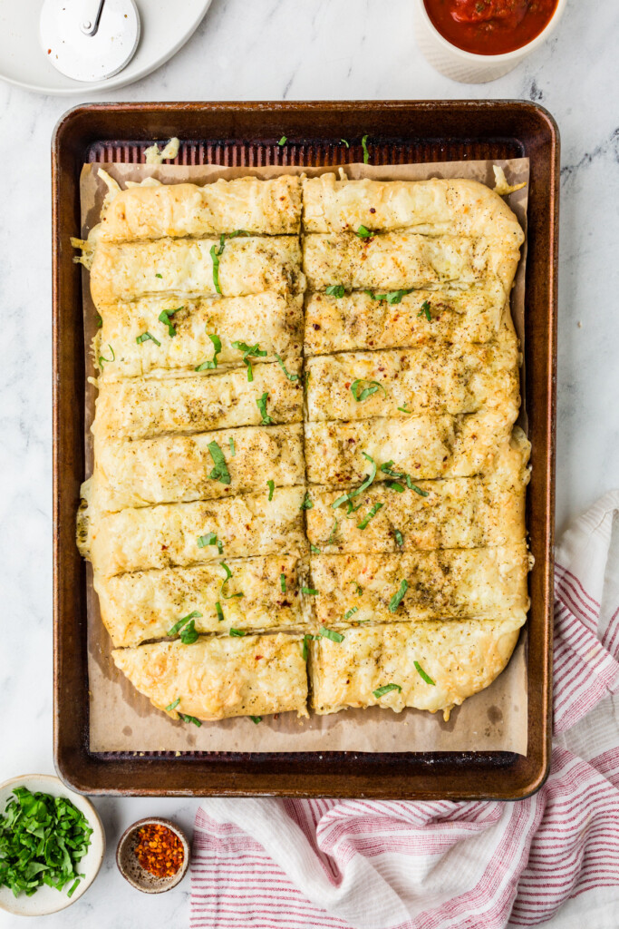 A freshly baked cheese breadsticks recipe with chopped basil.