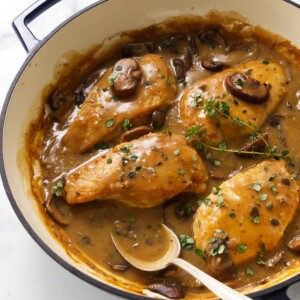 Chicken breasts in creamy mushroom sauce, garnished with thyme in Dutch oven.