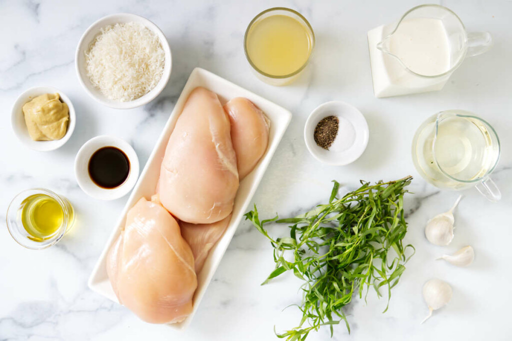 Ingredients used to make chicken in tarragon sauce on white marble.