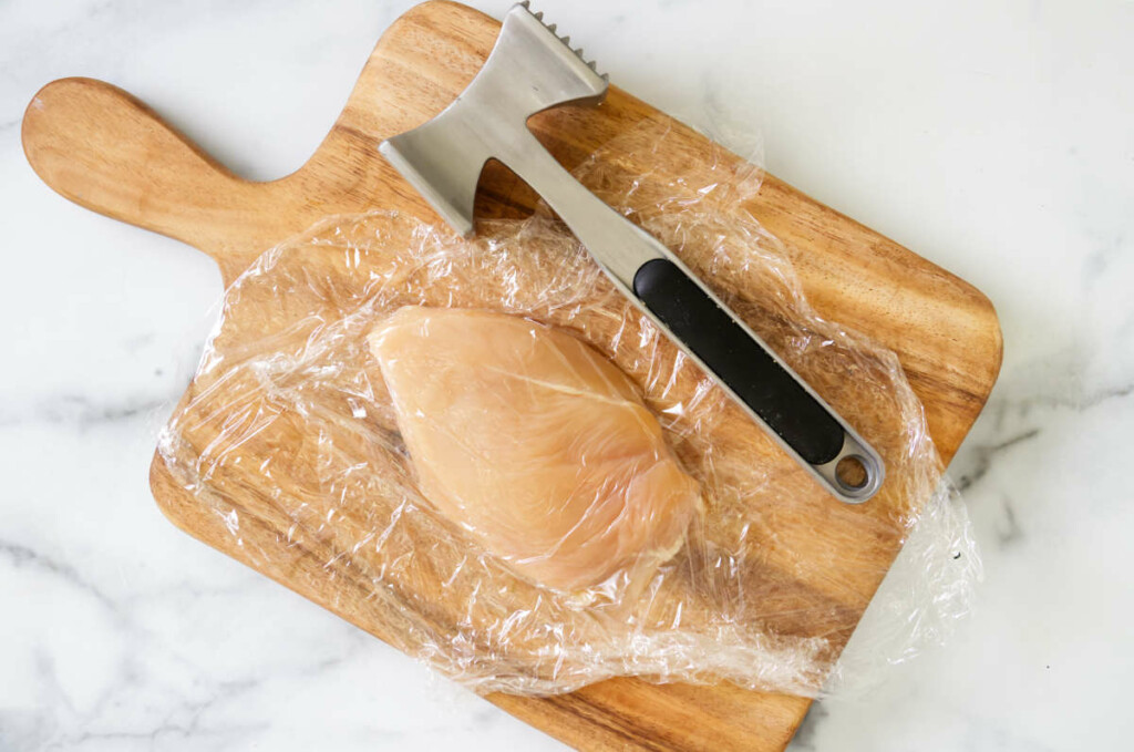 Using a meat mallet to pound a chicken breast.